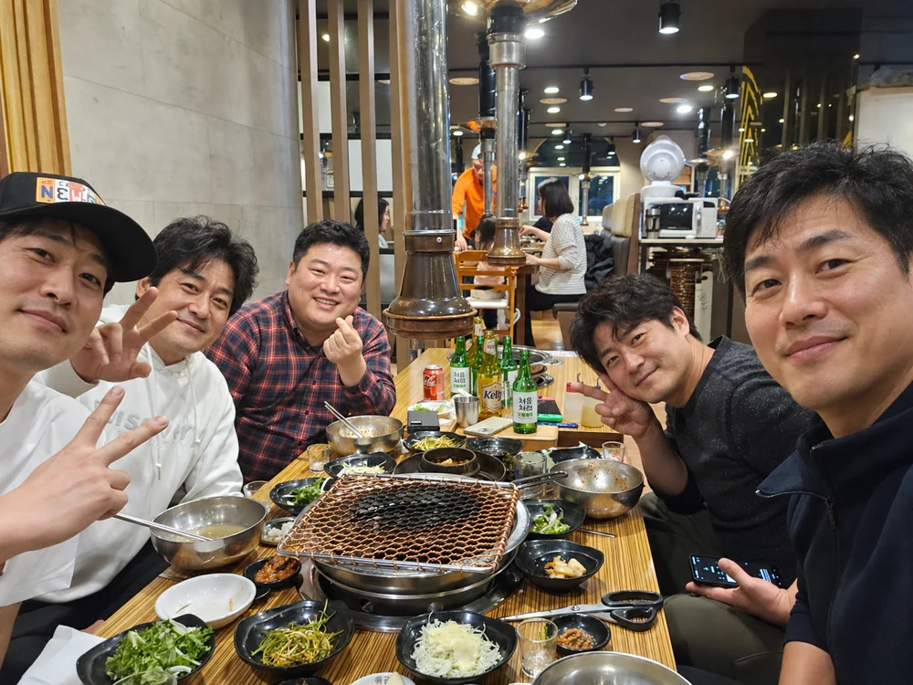 고깃집 식탁에 둘러앉아 사진을 찍는 친구들